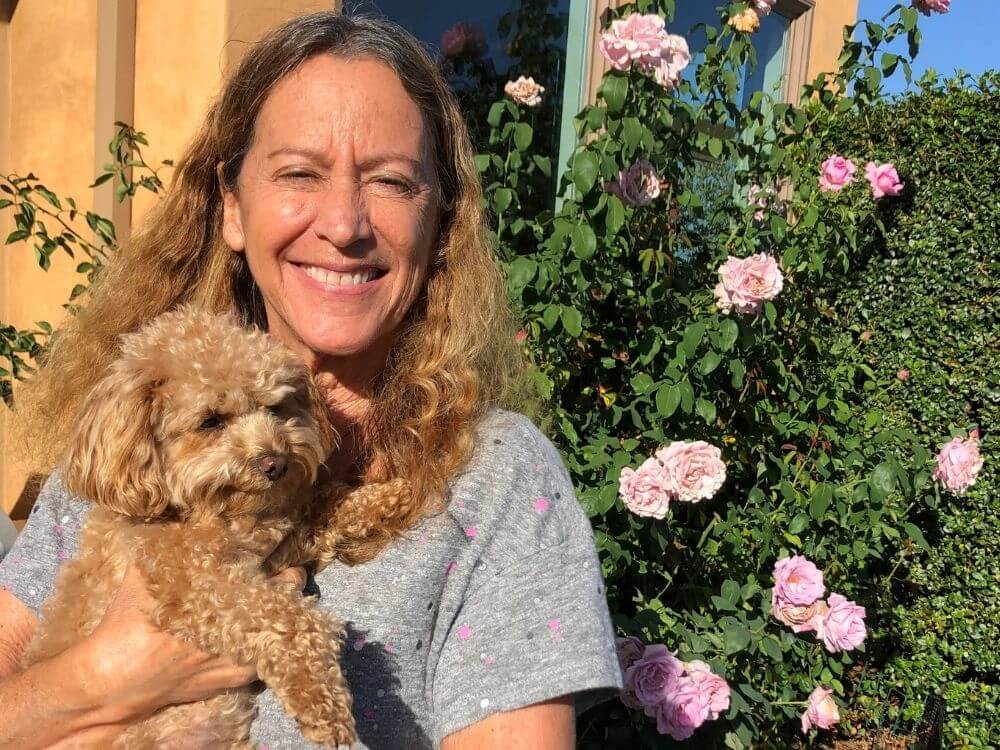 marji Pearson smiling holding brown hairy puppy